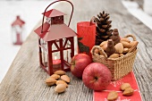 Weihnachtsdeko mit Äpfeln, Nüssen und Laterne auf Tisch