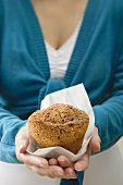 Woman holding muffin in paper napkin