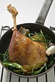 Fried goose leg with rosemary in frying pan