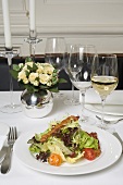 Salad with bacon & glasses of white wine on laid table