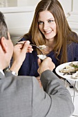 Man offering woman fresh oyster in restaurant
