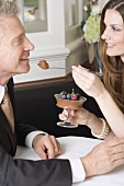 Frau reicht Mann Löffel mit Schokoladencreme im Restaurant