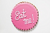 Biscuit with pink icing and the words 'Eat me!'