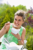 Woman eating tarator (Bulgarian yoghurt & cucumber soup) in garden