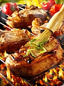 Brushing pork chop on barbecue rack with oil