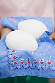 Hands holding two white eggs on rustic cloth