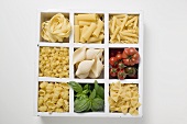 Various types of pasta, tomatoes and basil in type case