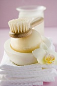 Perfumed soap in soap dish, towels, brush and windlight