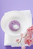 Soap with lather in white bowl on towel, orchids