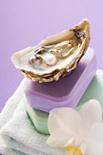 Oyster with pearl and two bars of soap on towel, orchid