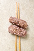 Dumplings coated in coconut on chopsticks (Japan)