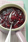 Red berry compote in pan with spoon