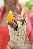 Frau hält Wrap mit Rindfleisch und Gemüse