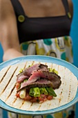 Woman serving tortilla with meat and vegetables
