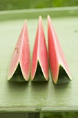 Three wedges of watermelon on green table