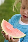Small girl holding a slice of watermelon with a bite taken