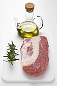Beef brisket on chopping board, rosemary, olive oil
