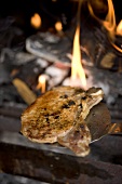 Fried pork chop on spatula in front of fire