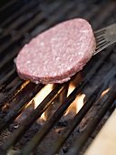 Placing a burger on a barbecue rack