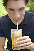 Young man drinking iced tea through a straw