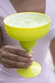 Frau hält grünes Glas mit Cocktail
