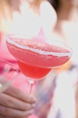 Hand holding a pink cocktail