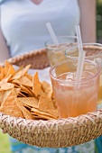 Woman serving basket of iced tea and tortilla chips