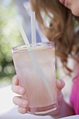 Woman holding a glass of lemonade with straws