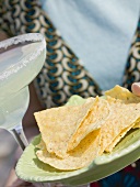 Frau hält Glas Margarita und Tortillachips (Mexiko)