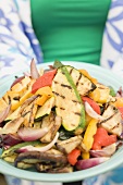 Woman holding a plate of grilled vegetables