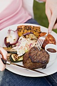 Seated woman eating grilled beef steak