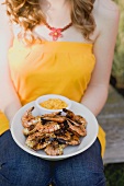 Woman holding a plate of grilled prawns