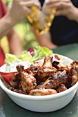 Grilled chicken wings, men with beer in background