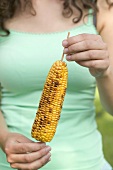 Woman holding grilled corn on the cob