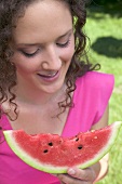 Frau hält angebissene Wassermelonenspalte