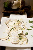 Cep carpaccio on chopping board in front of fresh cep