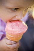 Small girl eating strawberry ice cream cone