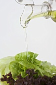 Pouring oil from carafe onto mixed salad leaves
