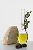 Olive oil in carafe, olives and piece of white bread