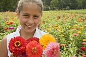 Girl with summer flowers in front of a field of flowers