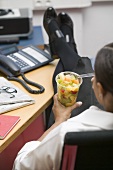 Frau isst Fruchtsalat im Büro