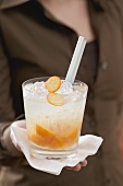 Woman serving drink with kumquats and ice cubes