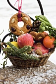 Lebkuchen mit Obst, Nüssen und Zapfen im Korb