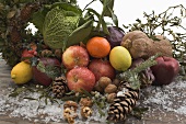 Obst, Gemüse, Nüsse, Tannenzapfen auf Holztisch im Freien