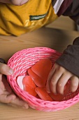 Kinderhand nimmt Zuckerherz aus Korb