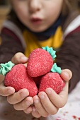 Child's hands holding marzipan strawberries