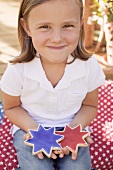 Small girl holding two star cookies (4th of July, USA)