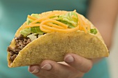 Hand hält Taco mit Hackfleisch und Käse