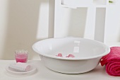 Wash bowl with flowers, soap, towel and candle in glass