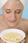 Woman with her hair wrapped in a towel, smelling herb tea